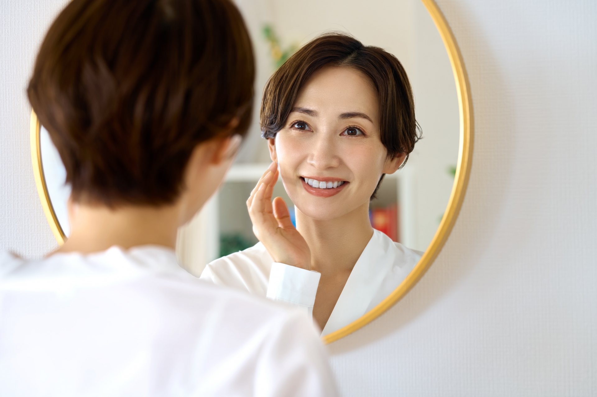 鏡を見て笑顔を浮かべる女性の様子