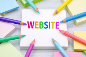 「website」と書かれた紙の周りに色とりどりの色鉛筆が置かれている画像