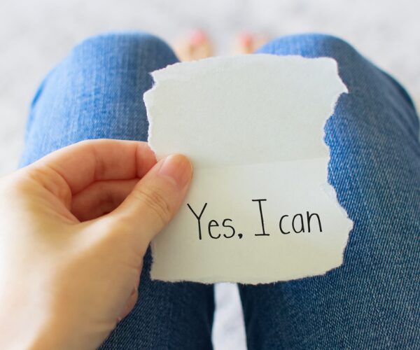 女性が「Yes, I can.」と書かれた紙を持っている